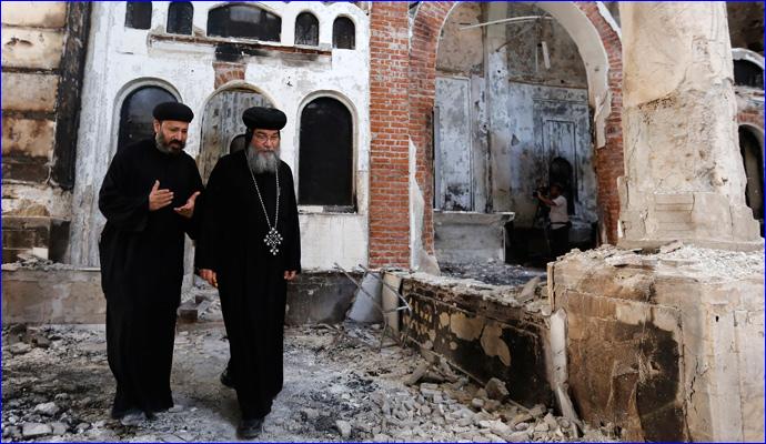 August 26, 2013: Bishop-General Macarius (right), a Coptic Orthodox leader, walks around the damaged Evangelical Church in Minya, south of Cairo (REUTERS/Louafi Larbi).