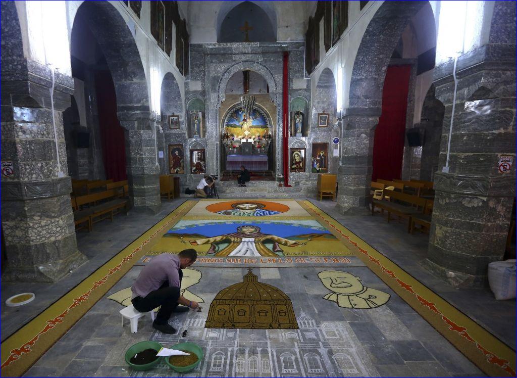 An Iraqi works on a temporary mosaic of Christian symbols made from the area's produce, including wheat, beans and lentils to commemorate an upcoming harvest feast, at the Chaldean Church of the Virgin Mary of the Harvest, in Alqosh, June 15, 2014 (AP photo).