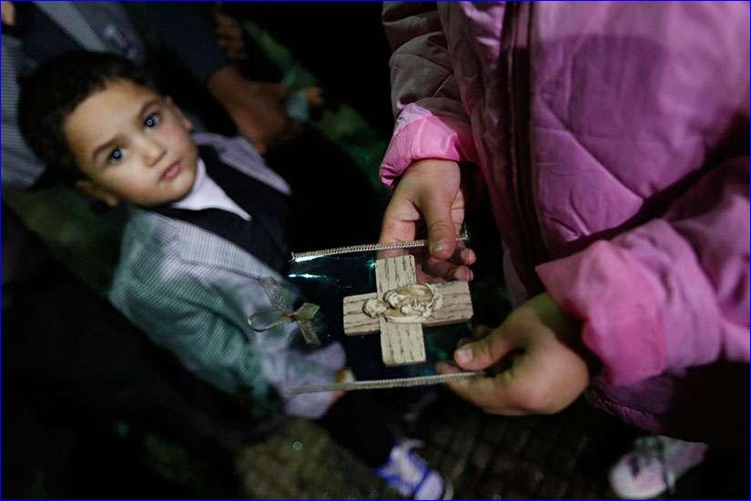 An Iraqi Christian refugee girl holds a souvenir of the Holy Family Dec. 12 as a boy looks on at a church in Hazmiyeh, near Beirut (CNS photo/Jamal Saidi, Reuters).