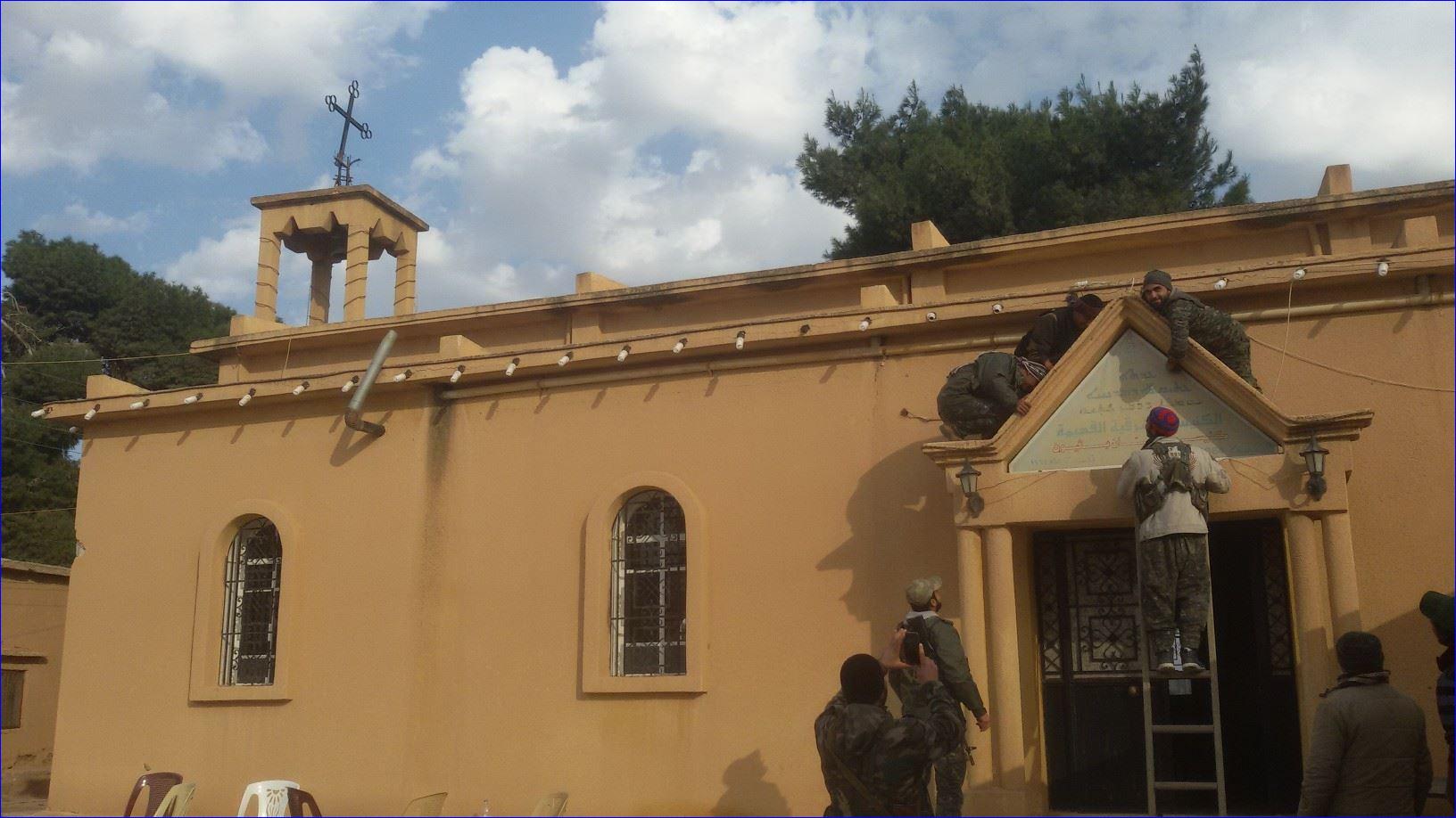 Assyrian fighters mounting the cross on the Church of St. Pithew in Tel Hurmizd (AINA photo).