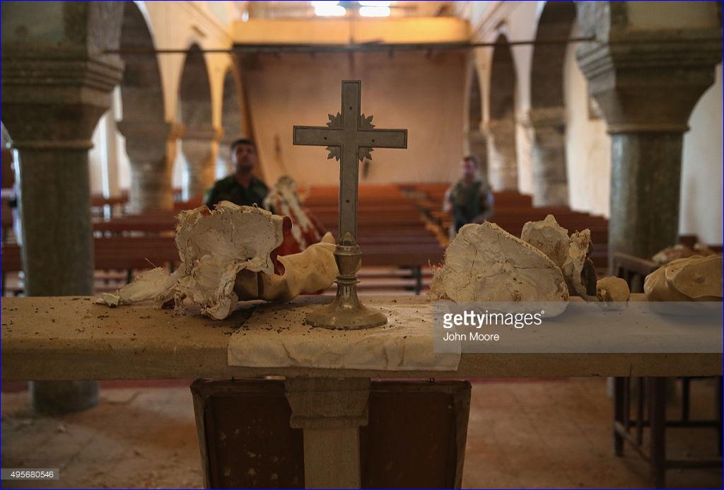 Christian militiamen look towards the rubble-strewn altar of the 13th century St. Jacob's Church on November 4, 2015 near the frontline with ISIS fighters in Telskuf, northern Iraq. All of the town's 11,000 predominantly Chaldean Catholic residents fled when it was overrun by the Islamic State in 2014 before being retaken by Peshmerga forces with the aid of American airstrikes. Of the 1,800 families that fled, some 40 percent left Iraq, according to Safaa Khamro, commander of the Nineveh Plain Forces (NPF), Christian militia. Many, he said, have now immigrated to Europe.